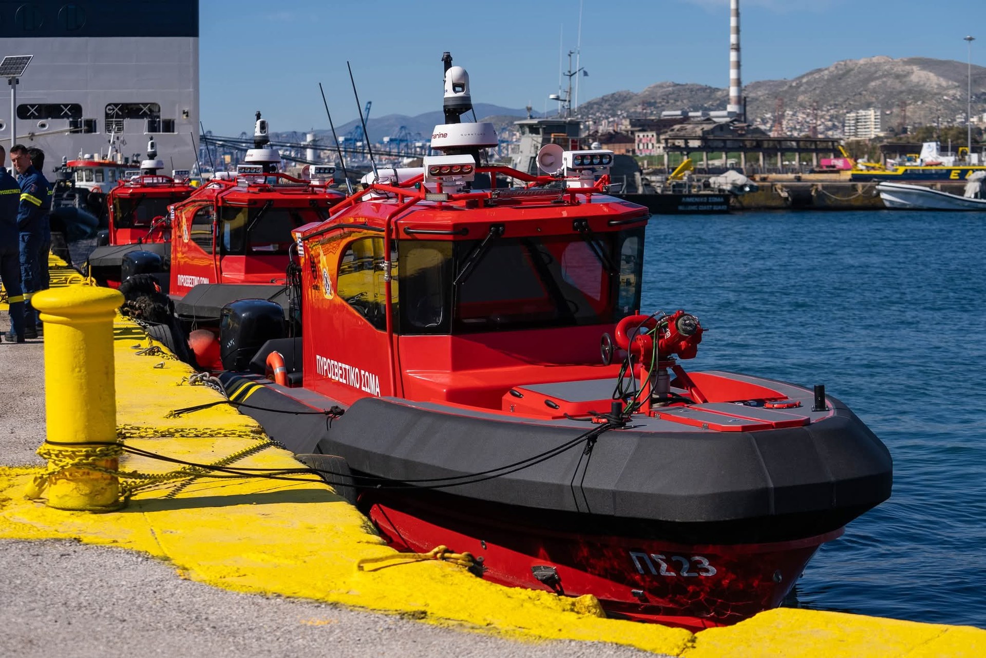 Red Rafnar fire fighting vessels with bow-mounted water cannons alongside a quay